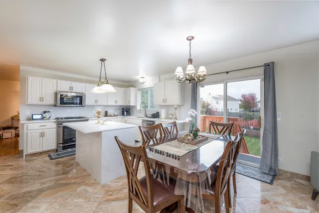 a view of a dining room and kitchen with a table chairs and a chandelier