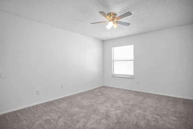 an empty room with a window and a fan