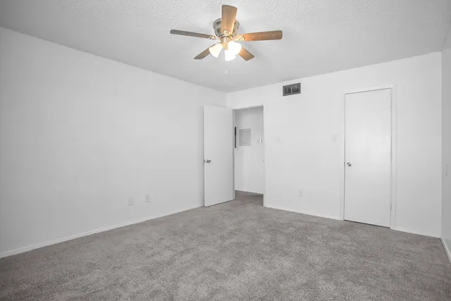 an empty room with closet and a ceiling fan