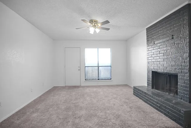 a view of an empty room with a fireplace and a window