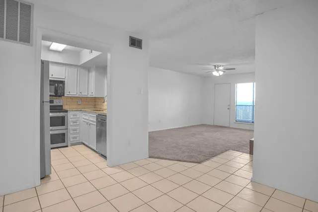 a view of a kitchen with a sink and an empty room