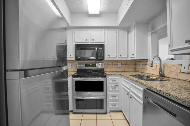 a kitchen with granite countertop white cabinets and stainless steel appliances