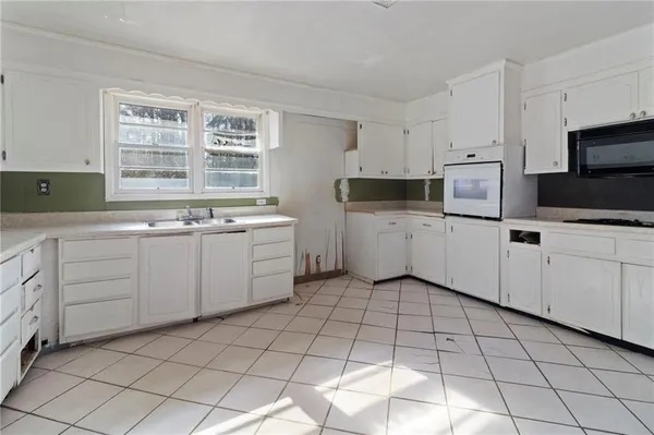a kitchen with white cabinets a sink dishwasher and a stove with wooden floor