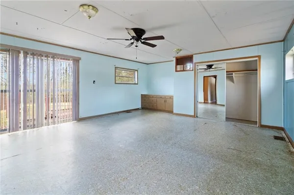 an empty room with windows and ceiling fan