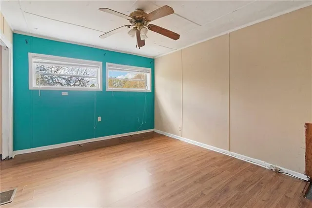 an empty room with wooden floor closet and windows