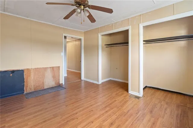 a view of empty room with wooden floor and fan