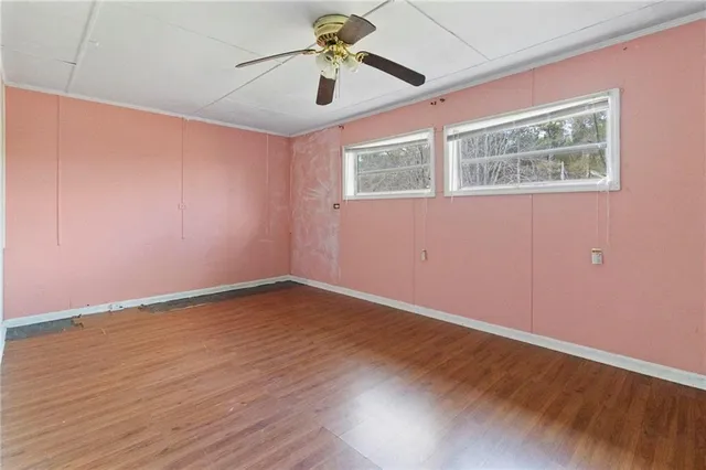 a view of an empty room with window and wooden floor