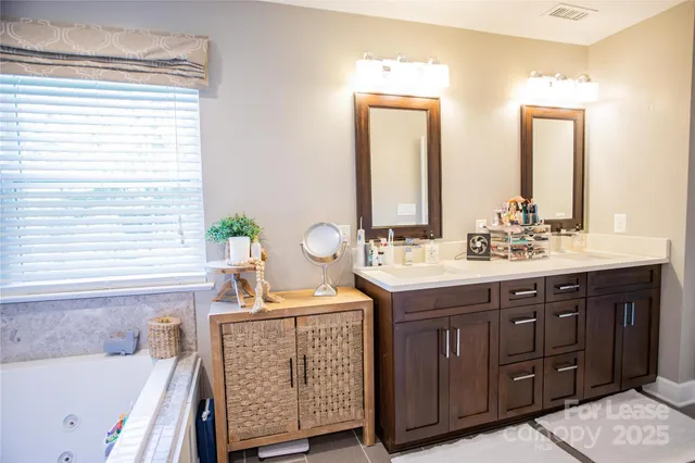 a bathroom with a sink double vanity granite tub shower and a mirror