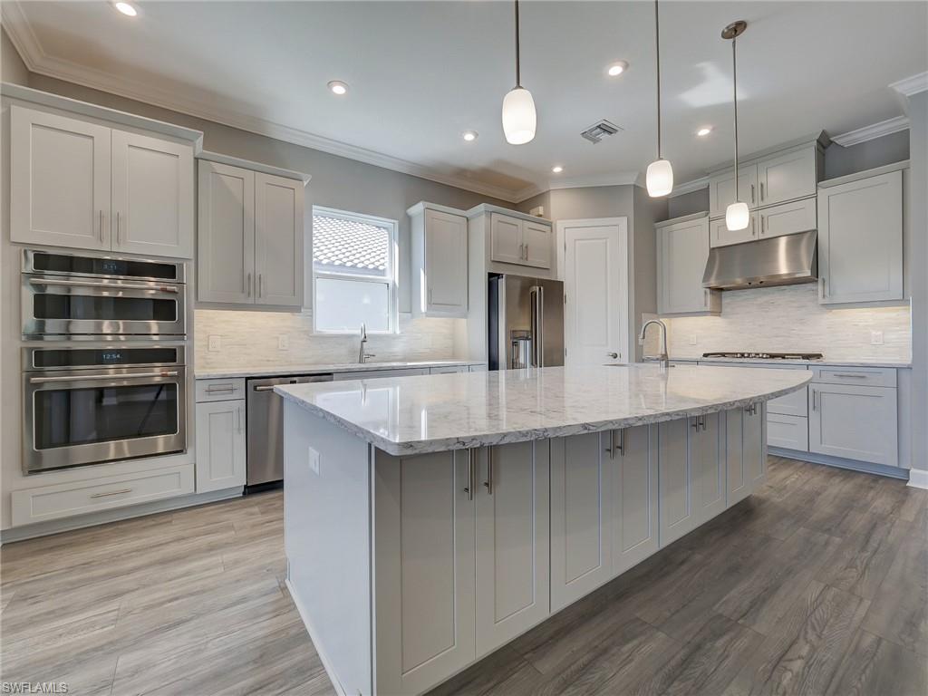 15107 Pescara Street Naples, FL 34114 - Photo 17 of 31 a kitchen with stainless steel appliances granite countertop a sink a stove and a wooden floors