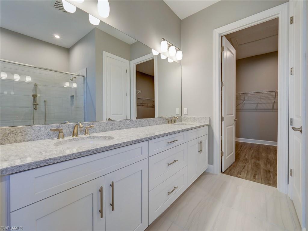 15107 Pescara Street Naples, FL 34114 - Photo 24 of 31 a spacious bathroom with a granite countertop sink a mirror and a shower