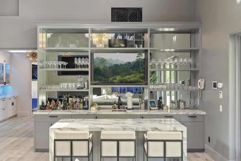 6853 Rancho Valencia Road Rancho Santa Fe, CA 92067 - Photo 26 of 40 a kitchen with a stove a sink and a dining table with wooden floor