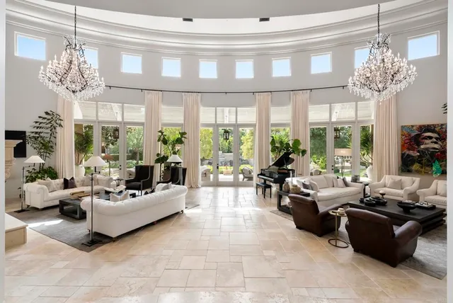 a living room with furniture a chandelier and a large window