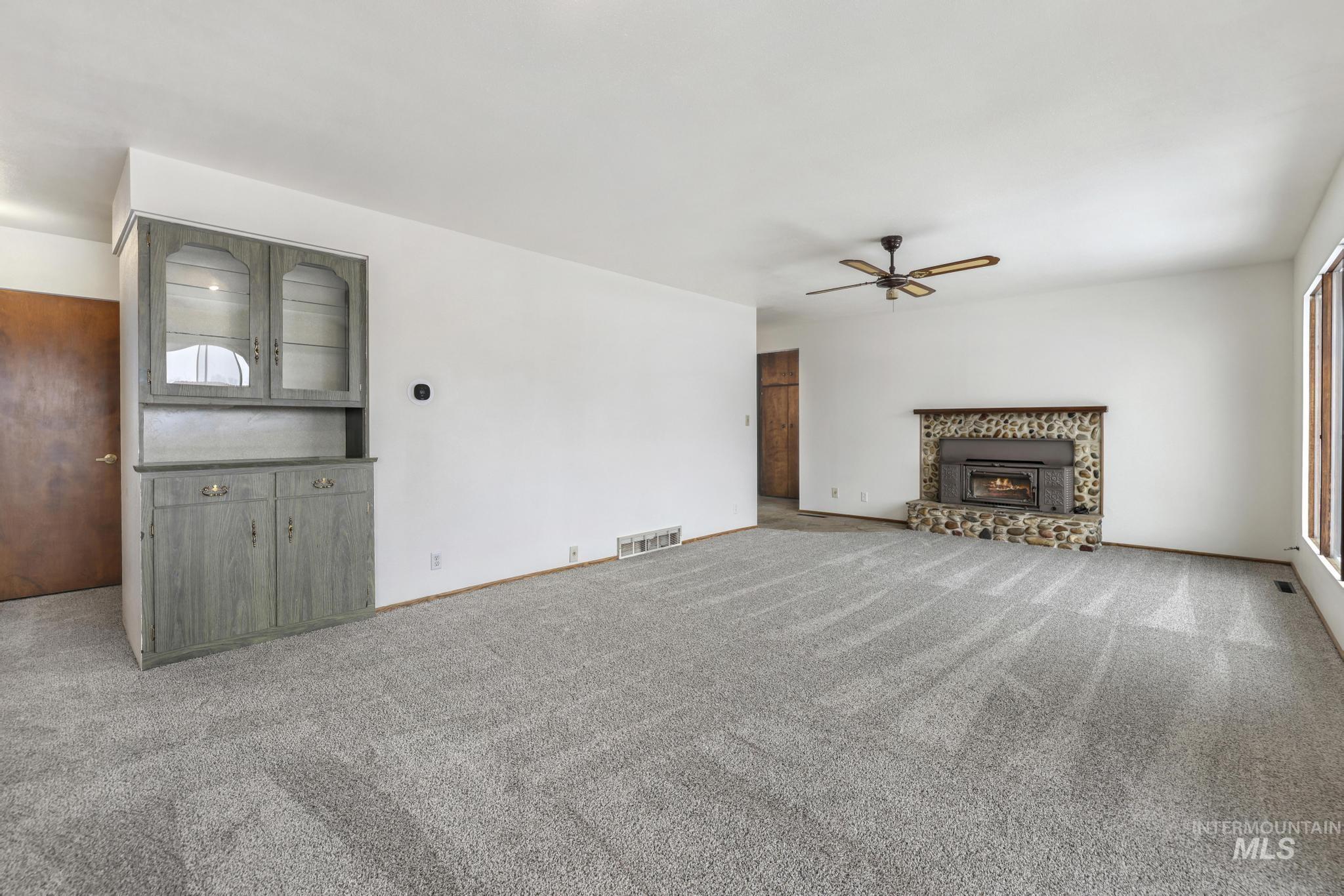 409 Clear Lakes Road Buhl, ID 83316 - Photo 13 of 43 Unfurnished living room with carpet flooring, a brick fireplace, and ceiling fan