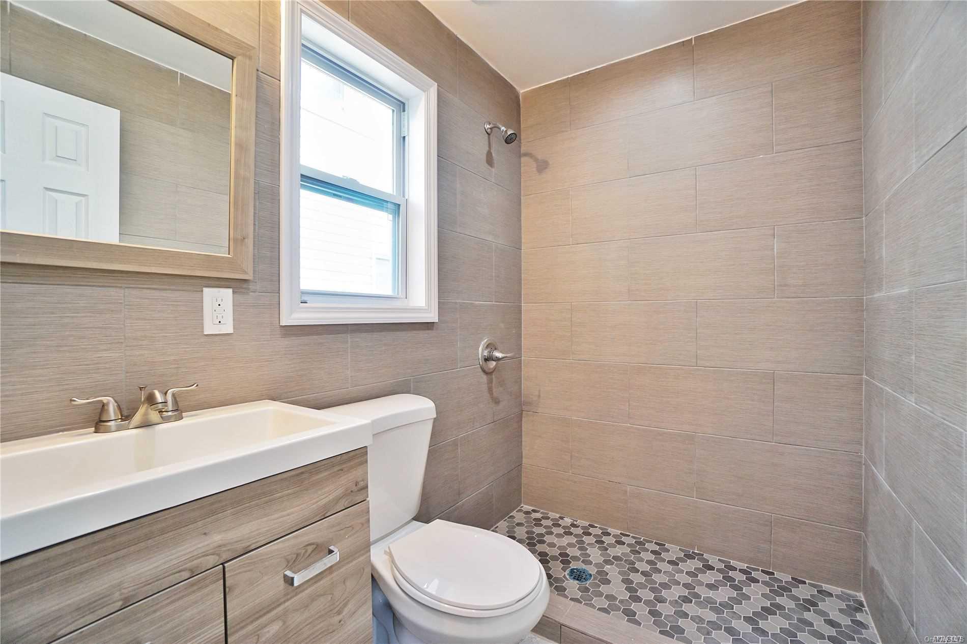 a bathroom with a sink a mirror a toilet and shower