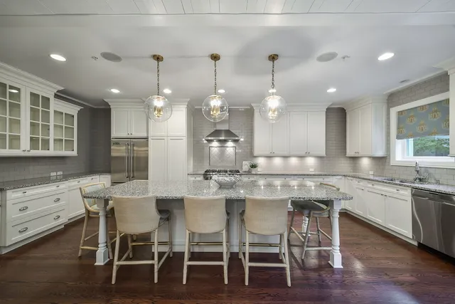 a kitchen with a dining table chairs wooden floor and appliances