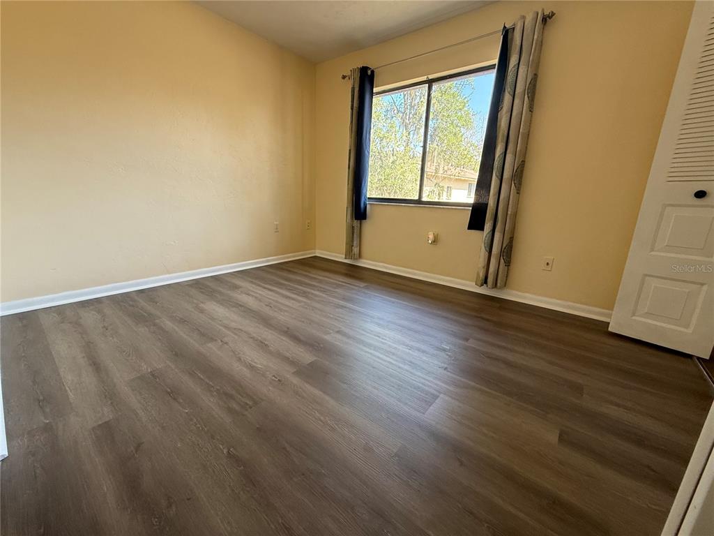 2735 Southwest 35th Place, Unit 1604 Gainesville, FL 32608 - Photo 22 of 25 a view of an empty room with wooden floor and a window