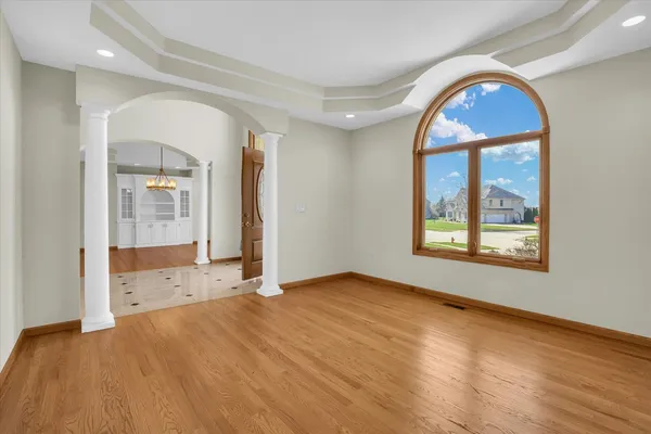 a view of an empty room with a window and wooden floor