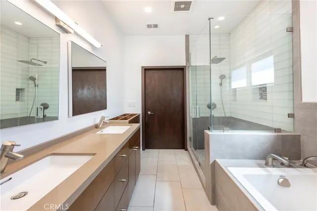 a bathroom with a tub double vanity sink and a large mirror