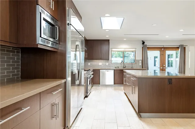 a kitchen with stainless steel appliances granite countertop a refrigerator oven a sink dishwasher and white cabinets next to a window