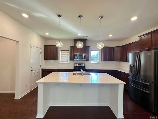 a large kitchen with a large counter top stainless steel appliances and cabinets