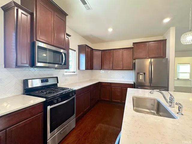 a kitchen with granite countertop a sink a stove top oven and refrigerator