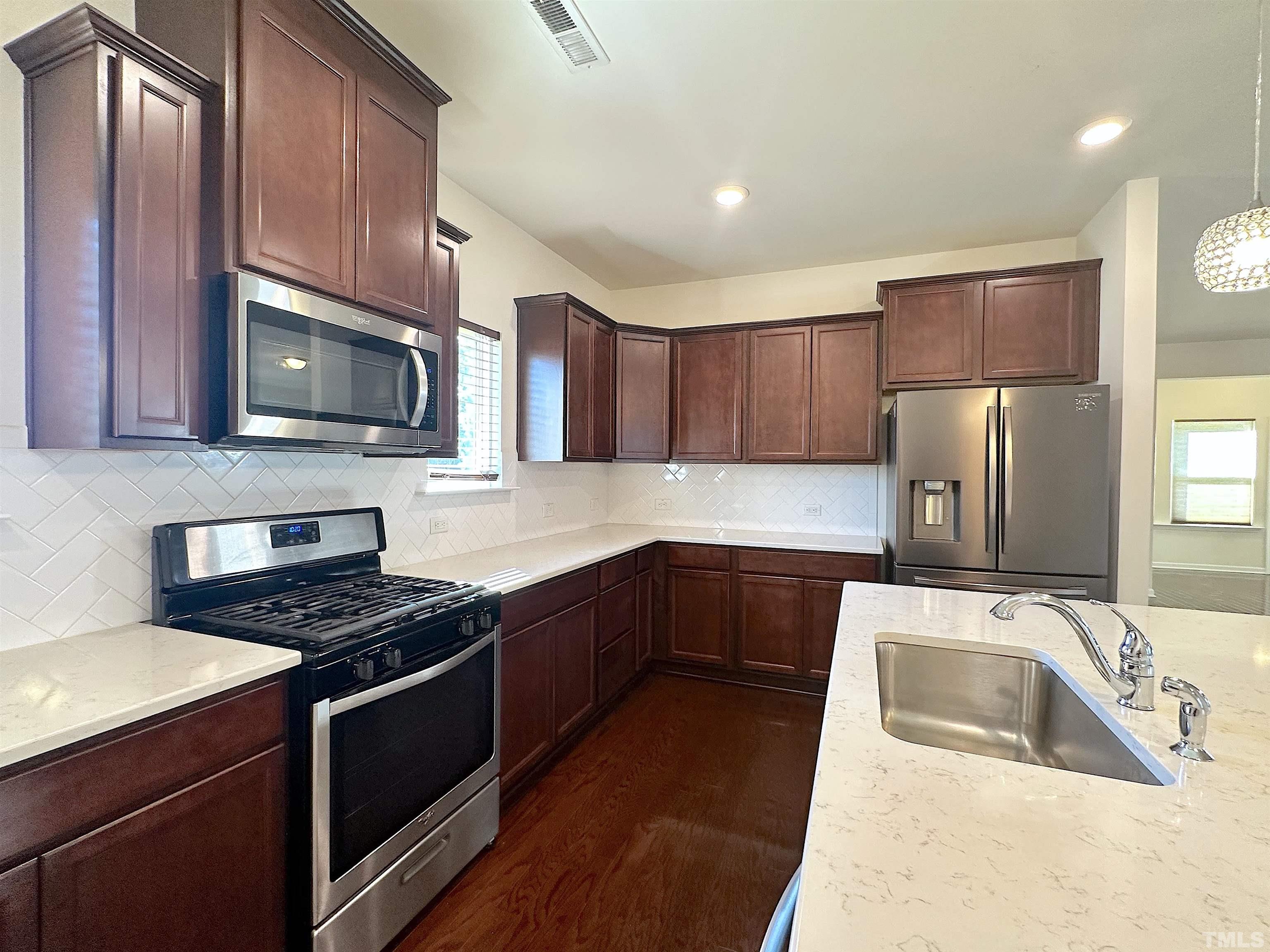 205 Azalea View Way Holly Springs, NC 27540 - Photo 9 of 29 a kitchen with granite countertop a sink a stove top oven and refrigerator