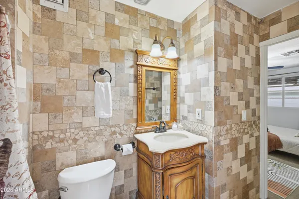 a bathroom with a granite countertop toilet sink and mirror