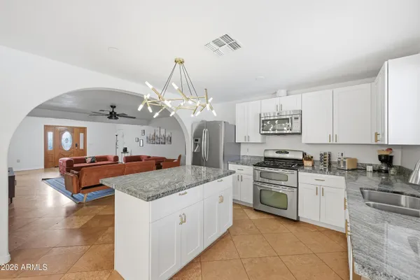 a kitchen with granite countertop a stove refrigerator and microwave