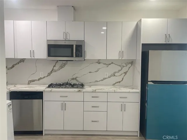 a kitchen with stainless steel appliances granite countertop a sink a stove and a microwave