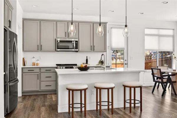 a kitchen with stainless steel appliances a stove a sink island and a refrigerator with wooden floor