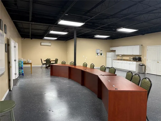 a kitchen with stainless steel appliances kitchen island granite countertop a table chairs and a refrigerator