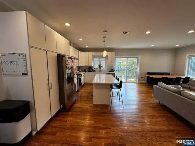 a living room with stainless steel appliances furniture refrigerator and a kitchen view