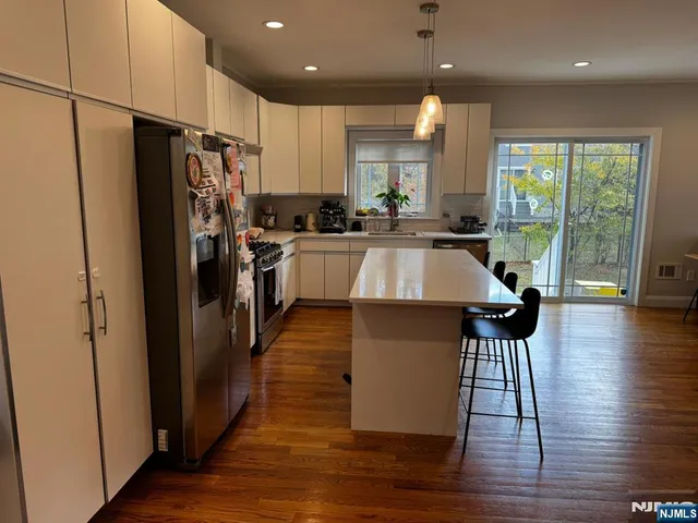 a kitchen with stainless steel appliances granite countertop a refrigerator a sink dishwasher a stove and white countertops with wooden floor