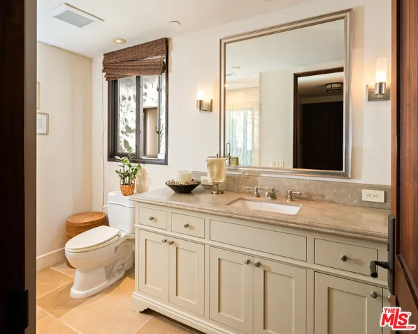 a bathroom with a granite countertop sink a toilet a mirror and bathtub