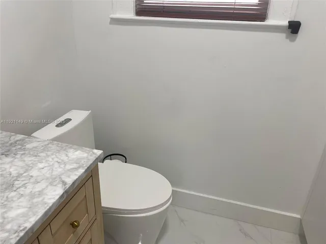 a bathroom with a granite countertop toilet and a sink