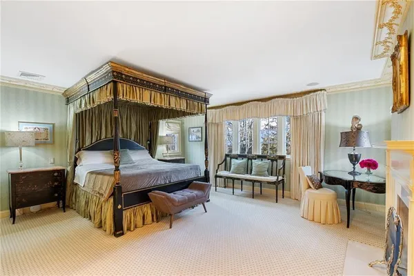 a bedroom with a bed a table and potted plants with wooden floor