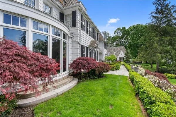 a view of a house with a big yard plants and large trees