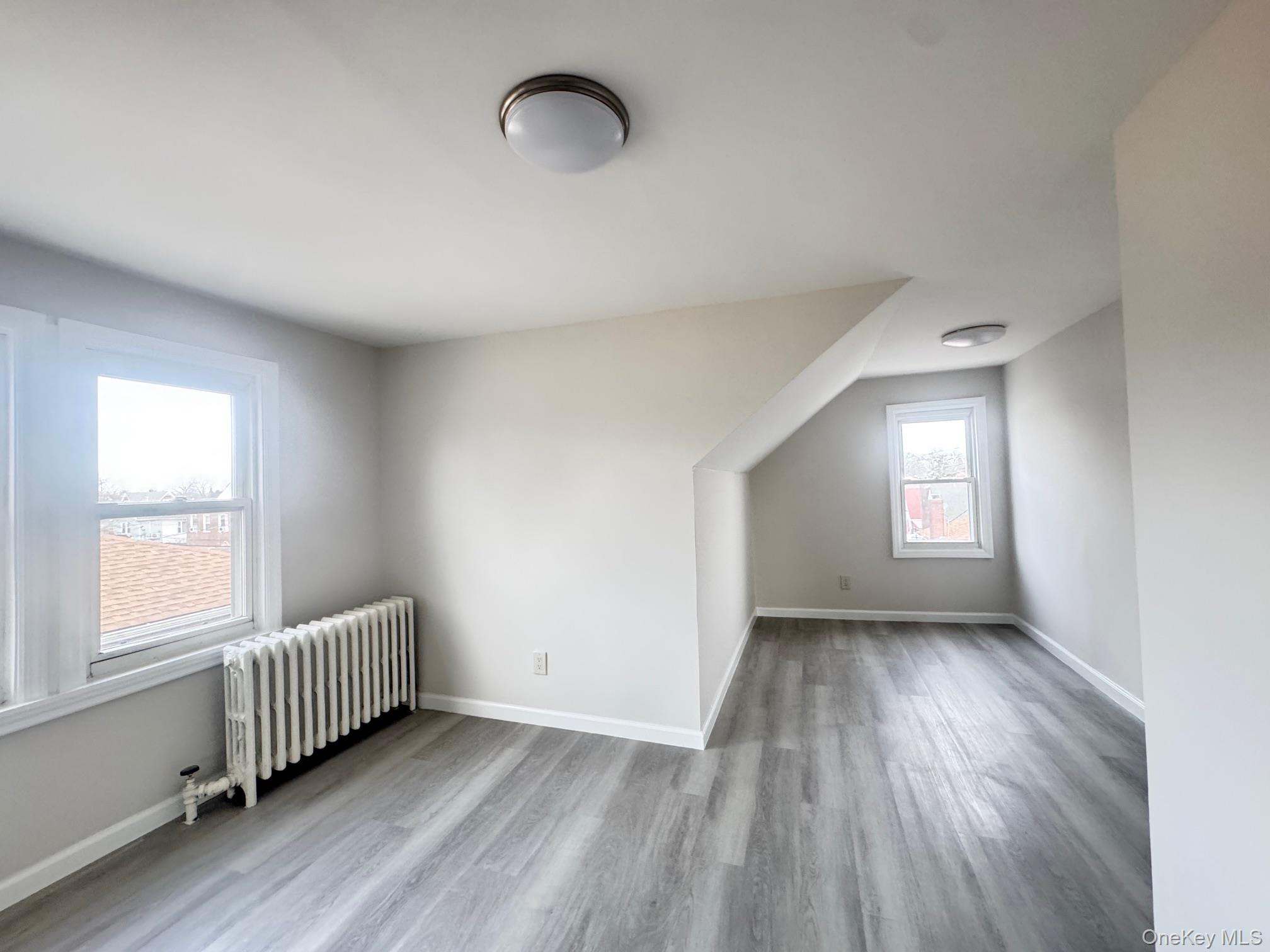 164-36 77th Road Queens, NY 11366 - Photo 12 of 20 an empty room with wooden floor and windows
