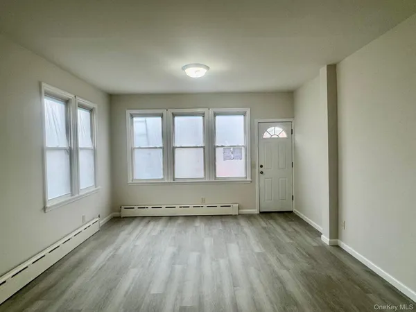 an empty room with wooden floor and window