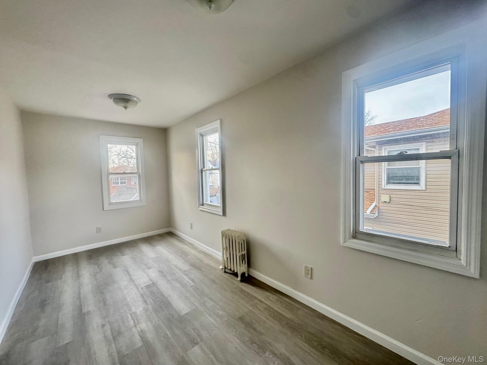 164-36 77th Road Queens, NY 11366 - Photo 8 of 20 a view of an empty room with a window and wooden floor