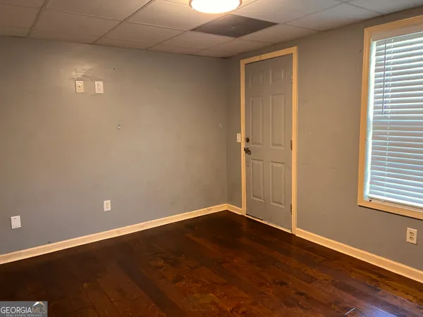 a view of an empty room with wooden floor and a window