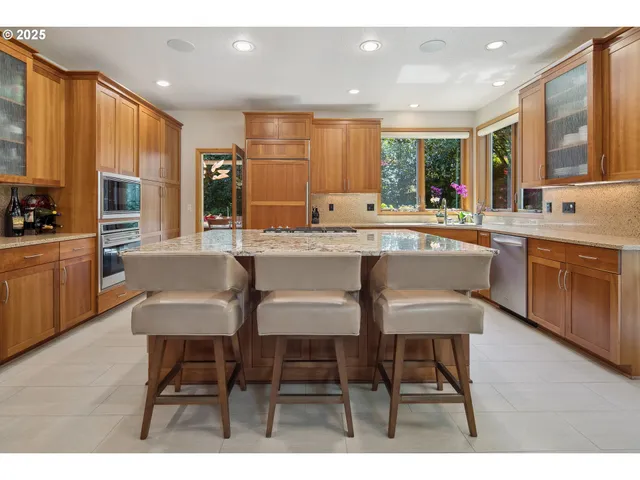 a kitchen with stainless steel appliances granite countertop table chairs sink and cabinets
