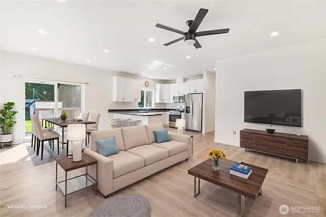 a living room with furniture and a flat screen tv with kitchen view