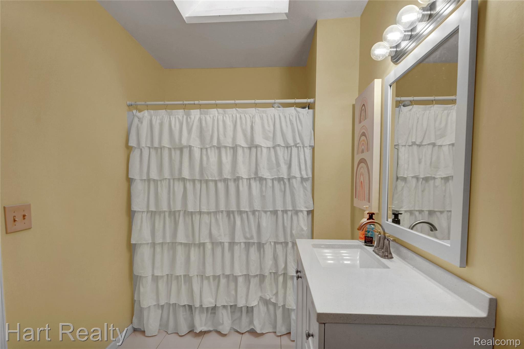 7167 Brown School Road North Branch, MI 48461 - Photo 28 of 51 Bathroom featuring a built-in vanity with an integrated sink, a large wall-mounted mirror, and overhead vanity lighting