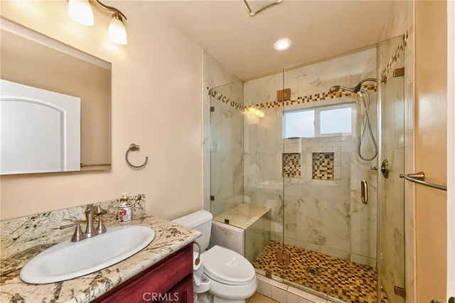 a bathroom with a sink a toilet a mirror and shower