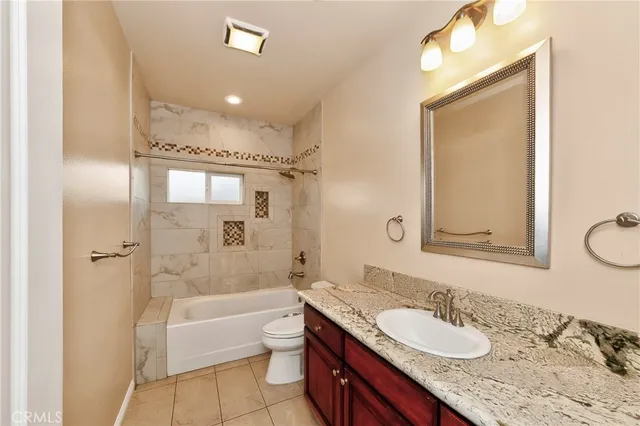 a bathroom with a granite countertop sink mirror toilet and bathtub