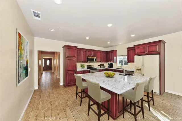 a kitchen with stainless steel appliances a dining table chairs and wooden floor