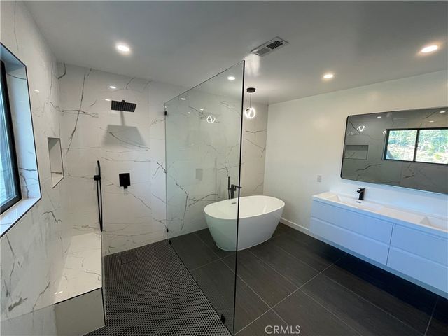 a bathroom with a double vanity sink a toilet a mirror and bathtub