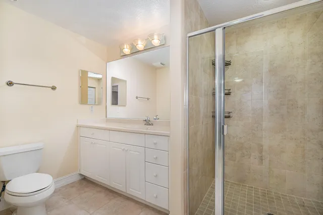 a bathroom with a granite countertop sink toilet a mirror a vanity and shower