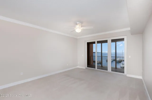 an empty room with chandelier fan and windows